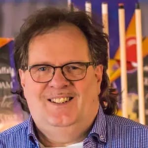 Portrait of a smiling man with glasses wearing a blue checkered shirt